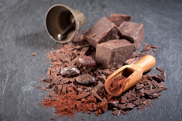 Foto fave di cacao al cioccolato e polvere di cacao su uno sfondo di pietra