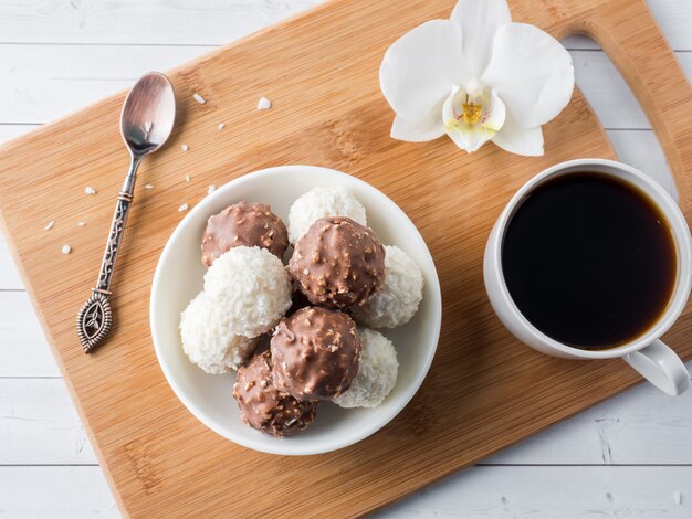 Chocolate and Coconut Candies in a Bowl on a Wooden tray Coffee Cup Orchid