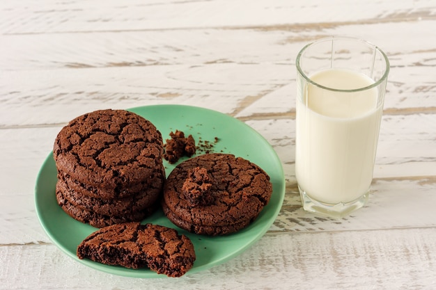 Chocolate cookies for breakfast with a glass of milk on a white wooden table.