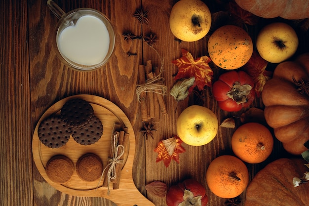 Chocolate cookies vegetables fruit and milk in a mug baking with cinnamon sticks on a wooden backgro...