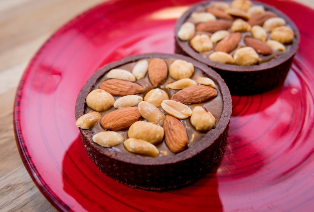 Chocolate cookies with almond nuts on a red plate. Restaurant.