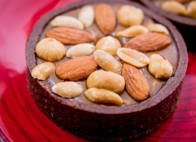 Chocolate cookies with almond nuts on a red plate. Restaurant.