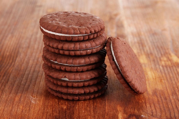 Chocolate cookies with creamy layer on wooden table closeup