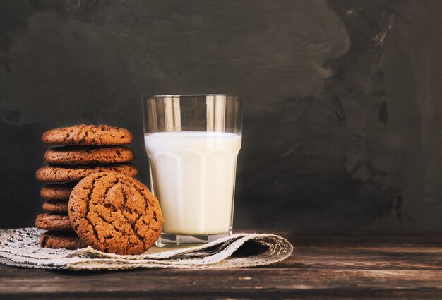 暗いコンクリートの壁に牛乳とチョコレートクッキー。セレクティブフォーカス。