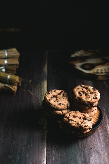 木製のテーブルにチョコレートクッキー。チョコレートチップクッキーを黒で撮影