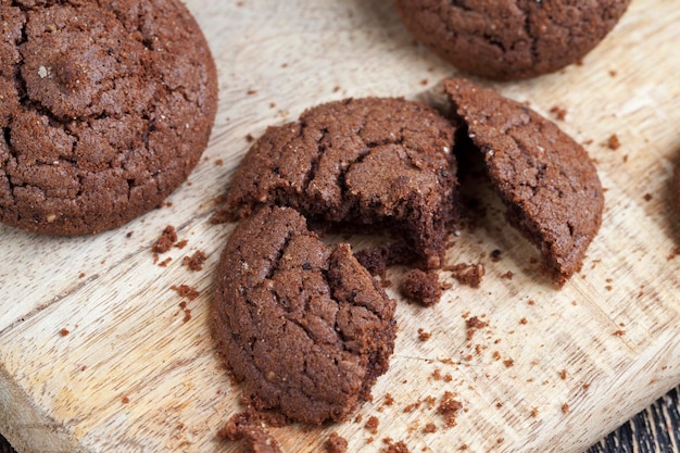 Photo chocolate cookies on a wooden table roundshaped cookies made of flour and a large amount of cocoa