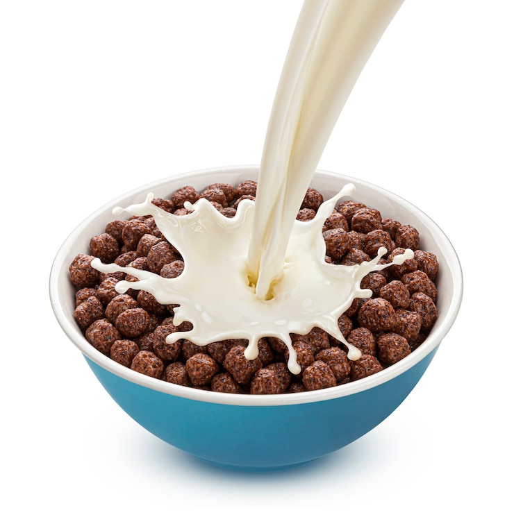 Photo chocolate corn balls with pouring milk isolated on white background