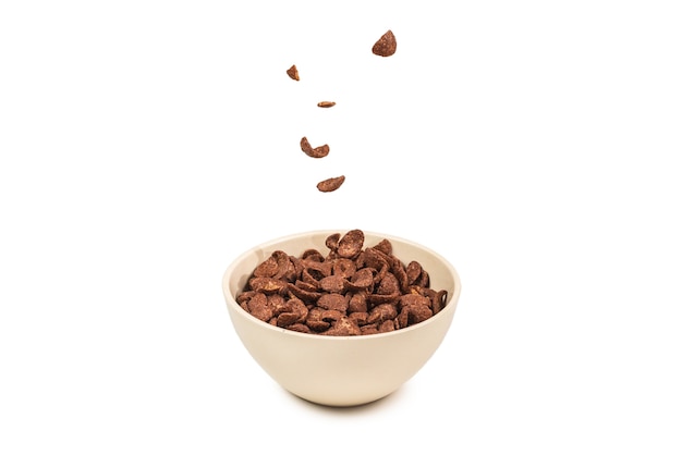 Chocolate corn flakes falling to the white bowl isolated on white background.