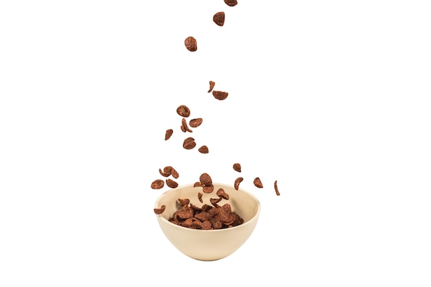 Chocolate corn flakes falling to the white bowl isolated on white. Motion. Copyspace.