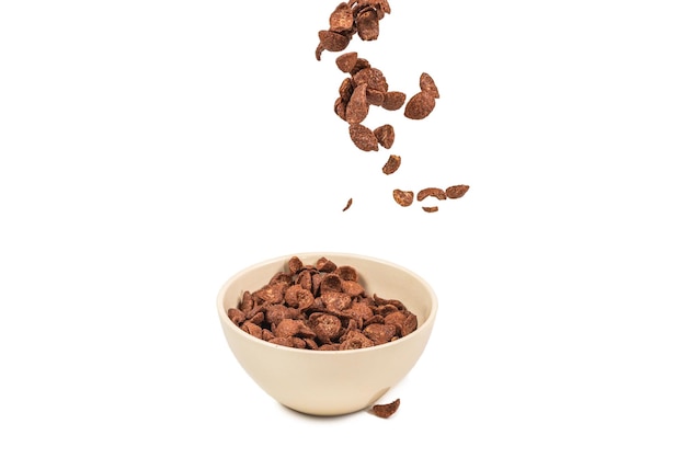 Chocolate corn flakes falling to the white bowl isolated on white. Motion. Copyspace.