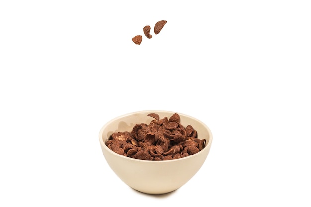 Photo chocolate corn flakes falling to the white bowl isolated on white. motion. copyspace.