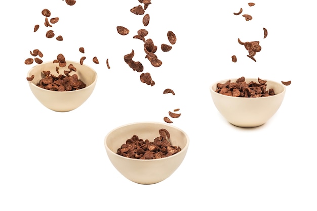 Photo chocolate corn flakes falling to the white bowl isolated on white