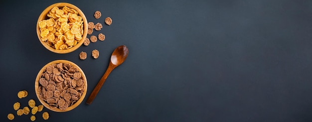 Foto fiocchi di mais al cioccolato per la colazione nel piatto di bambù su sfondo nero. fiocchi di mais sani. colazione mattutina. bandiera. vista dall'alto con spazio di copia.