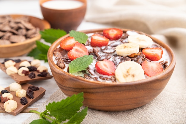 Chocolate cornflakes with milk and strawberry in wooden bowl