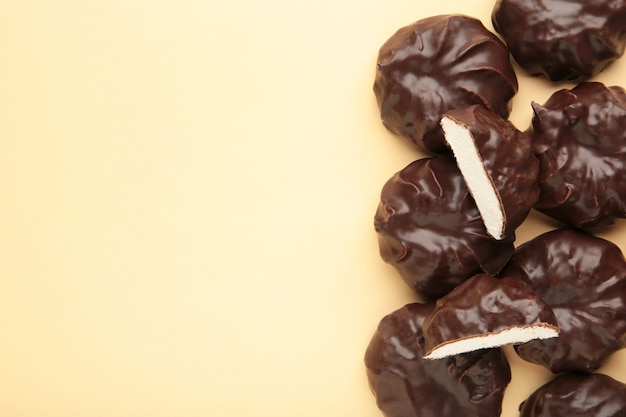 Chocolate covered marshmallows on beige surface with copy space