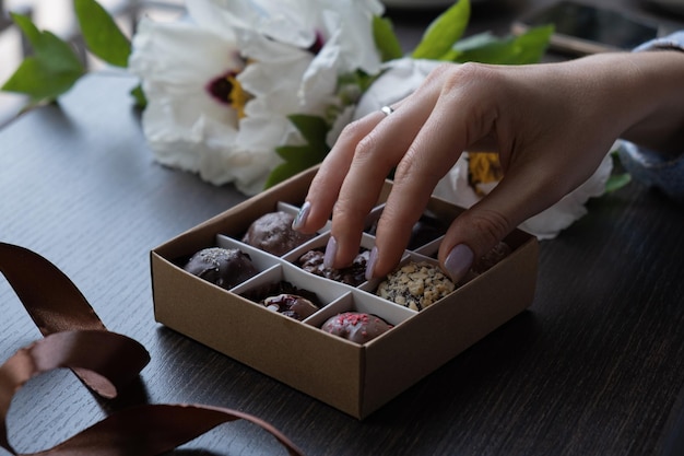 Chocolate craft candy in female hand and candy box