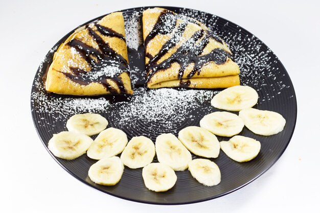 Chocolate crepes with banana on the plate, studio shoot