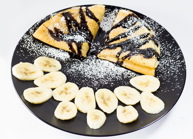 Chocolate crepes with banana on the plate, studio shoot