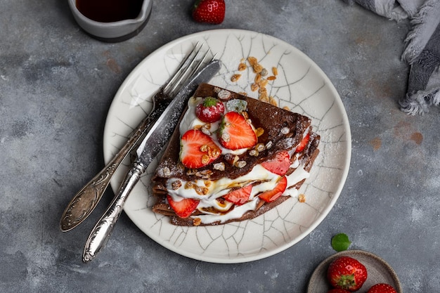 Chocolate crepes with cream cheese and strawberries for Breakfast