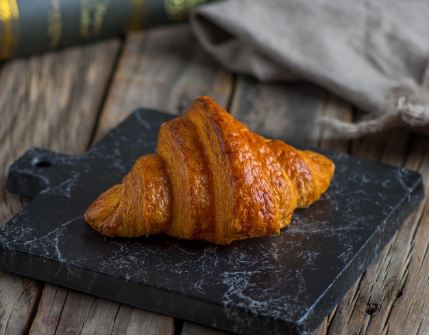 Chocolate croissant served in a dish isolated on cutting board side view of breakfast on background