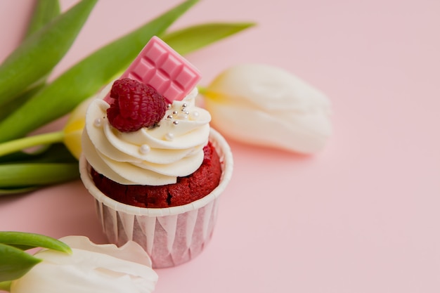 chocolate cupcake and white tulips on a pink space