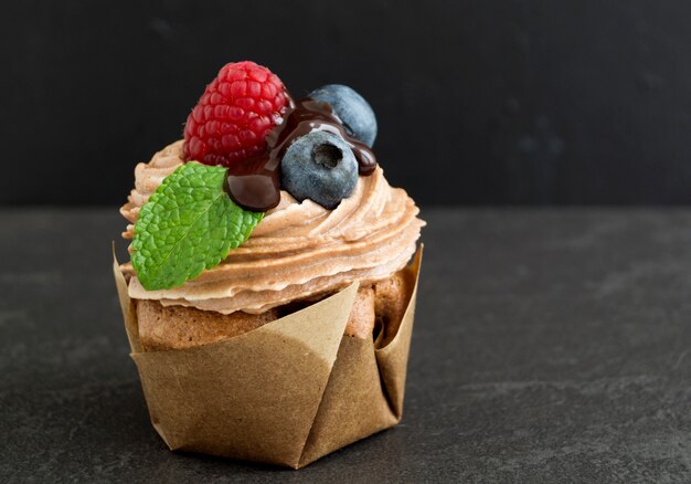 黒い背景にチョコレートクリームとチョコレートのカップケーキ。