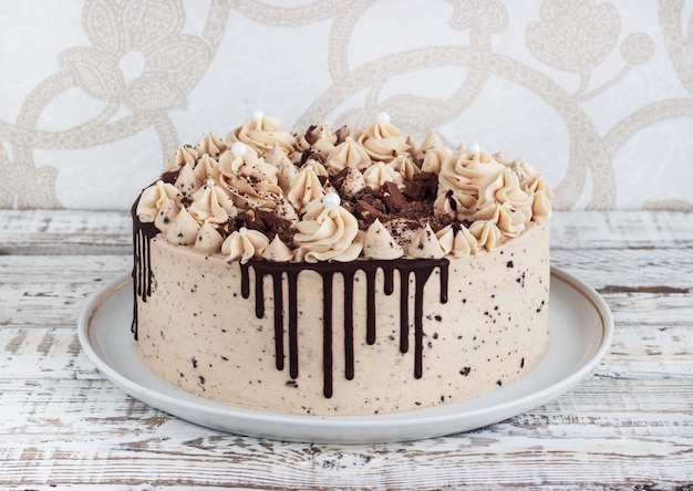 グランジ白い木製の背景にムースクリームのアイシングとチョコレートケーキ