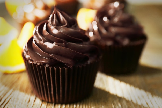 Chocolate cupcakes and cut orange on wooden table