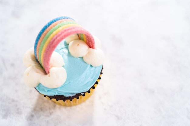 Cupcakes al cioccolato decorati con glassa di crema al burro blu e arcobaleno per la festa di compleanno a tema unicorno