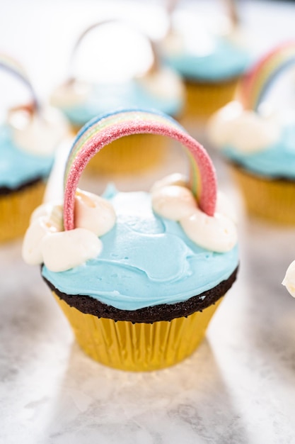 Cupcakes al cioccolato decorati con glassa di crema al burro blu e arcobaleno per la festa di compleanno a tema unicorno