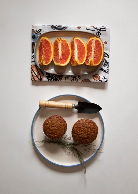 Chocolate cupcakes in a plate with sliced oranges and a small shovel on a white background