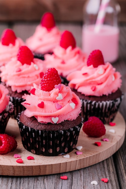 Chocolate cupcakes with pink cream sugar hearts and fresh raspberries for St Valentine's Day