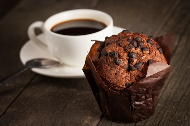 Foto muffin al cioccolato scuro cotto con menta su un tavolo di legno con cannella, anice, cioccolato.