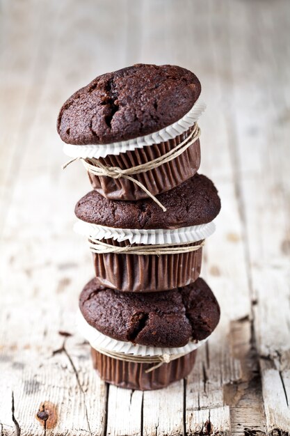 Chocolate dark muffins on rustic wooden table.