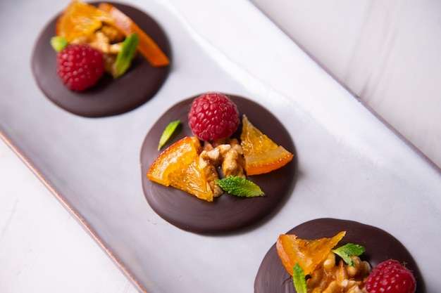 Photo chocolate dessert with candied orange, raspberry and nuts.