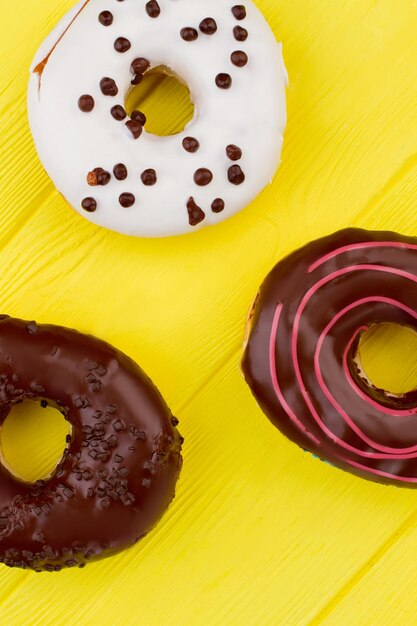 Chocolate donuts on color background. Pastry decorated with icing. Yummy treats with frosting.