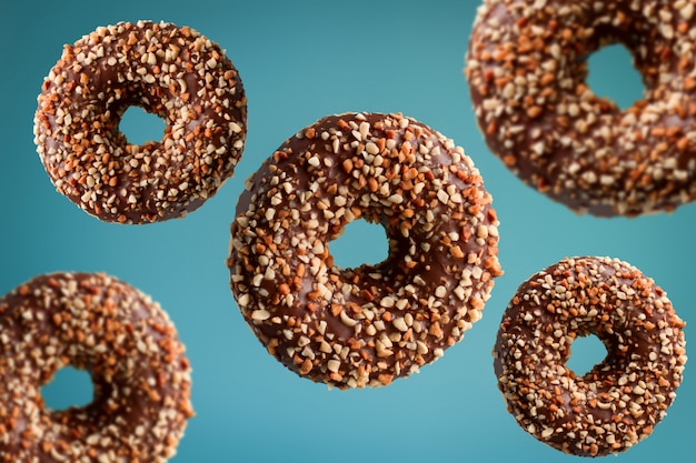 Chocolate donuts with peanuts flying over blue background, junk food concept