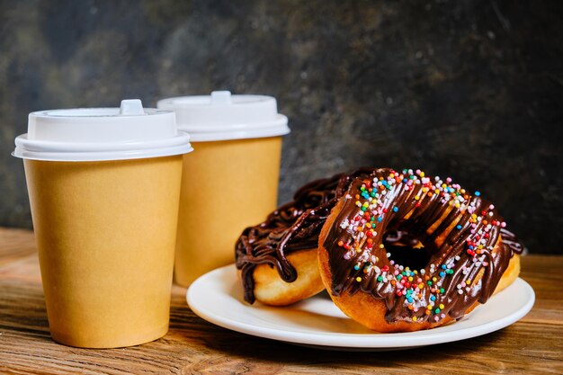 Chocolate doughnuts and takeaway coffee on a dark background.