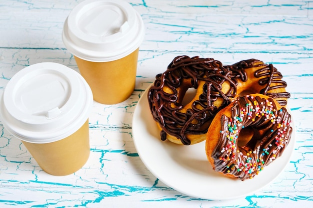 chocolate doughnuts and takeaway coffee on a light background.