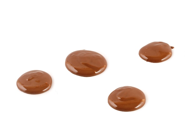 Chocolate drops of liquid chocolate sauce isolated on white\
background melted drops of chocolate