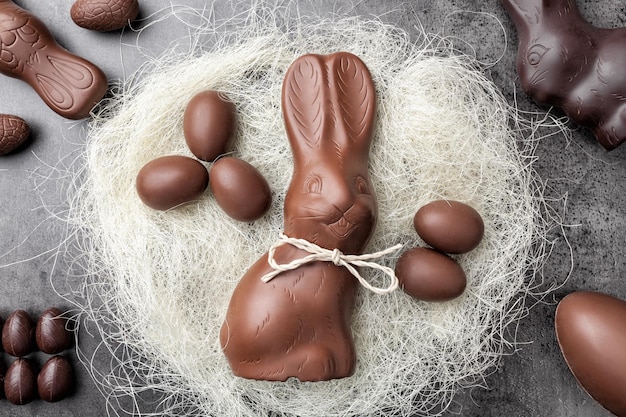 Chocolate Easter bunny and eggs in a nest on rustic background