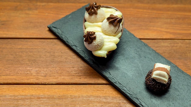 Uovo di pasqua al cioccolato e tartufo al cioccolato sopra la pietra nera con fondo in legno