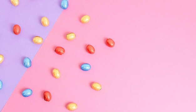 Chocolate easter eggs in a colorful wrapper on a lilacpink background