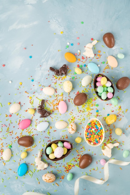 chocolate easter eggs rabbits and sweets on a blue concrete background Easter composition Copy space