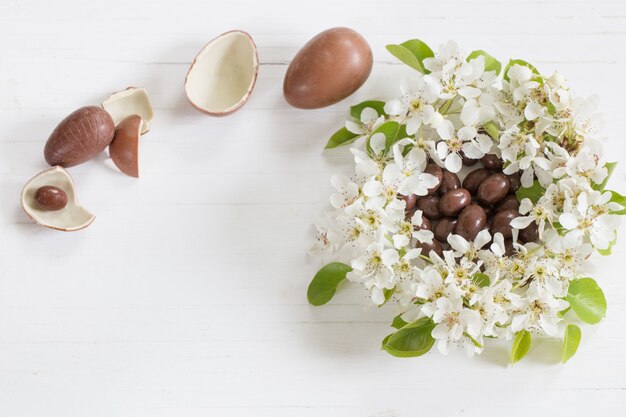 Chocolate Easter eggs with spring flowers on wooden background