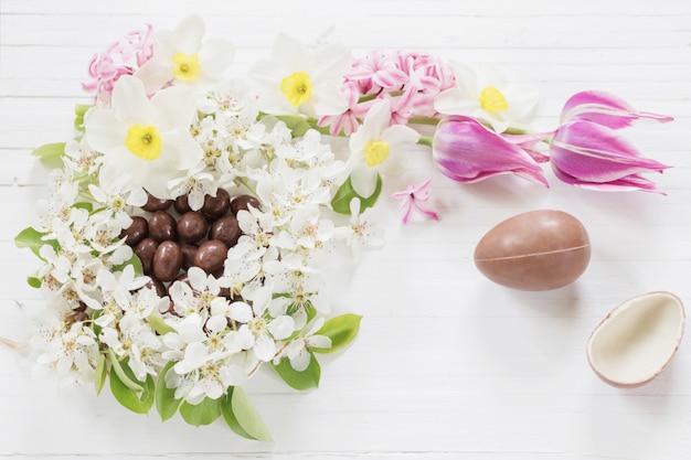 木製の背景の春の花とチョコレートのイースターエッグ