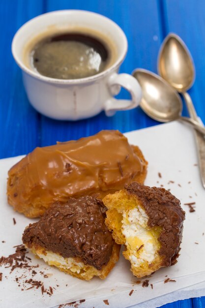 Chocolate eclairs on white dish on wooden surface