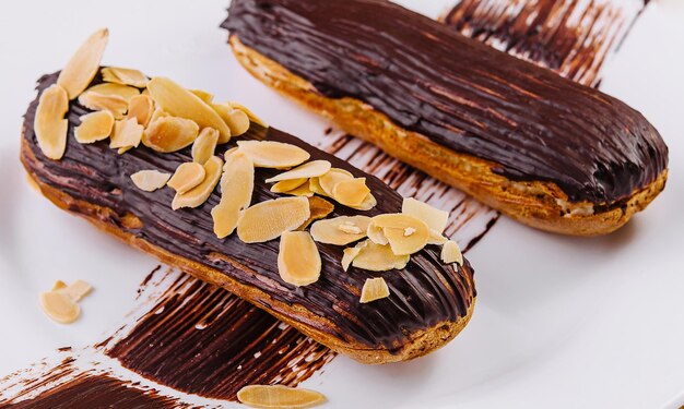 Chocolate eclairs with almonds on plate