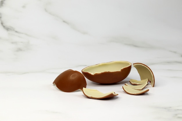 chocolate egg broken into pieces on a light background