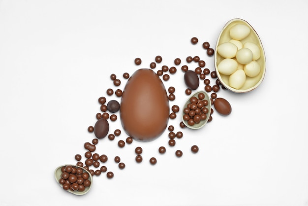 Chocolate eggs and candies on white background